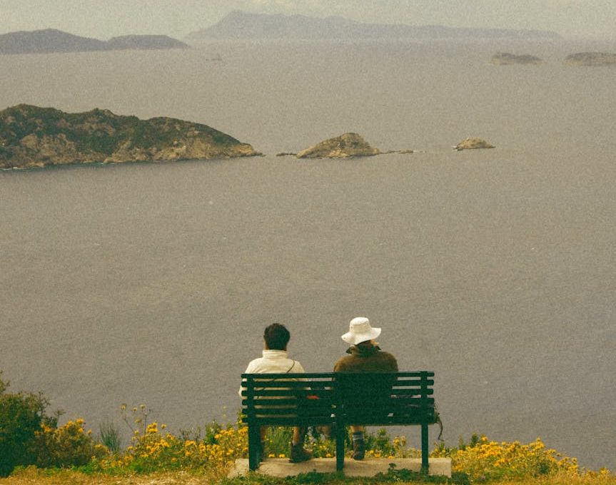 woman and man sitting on bench on sea shore