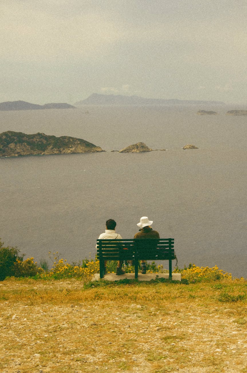 woman and man sitting on bench on sea shore