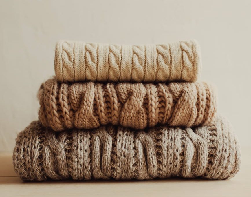 stack of knitted sweaters on white surface