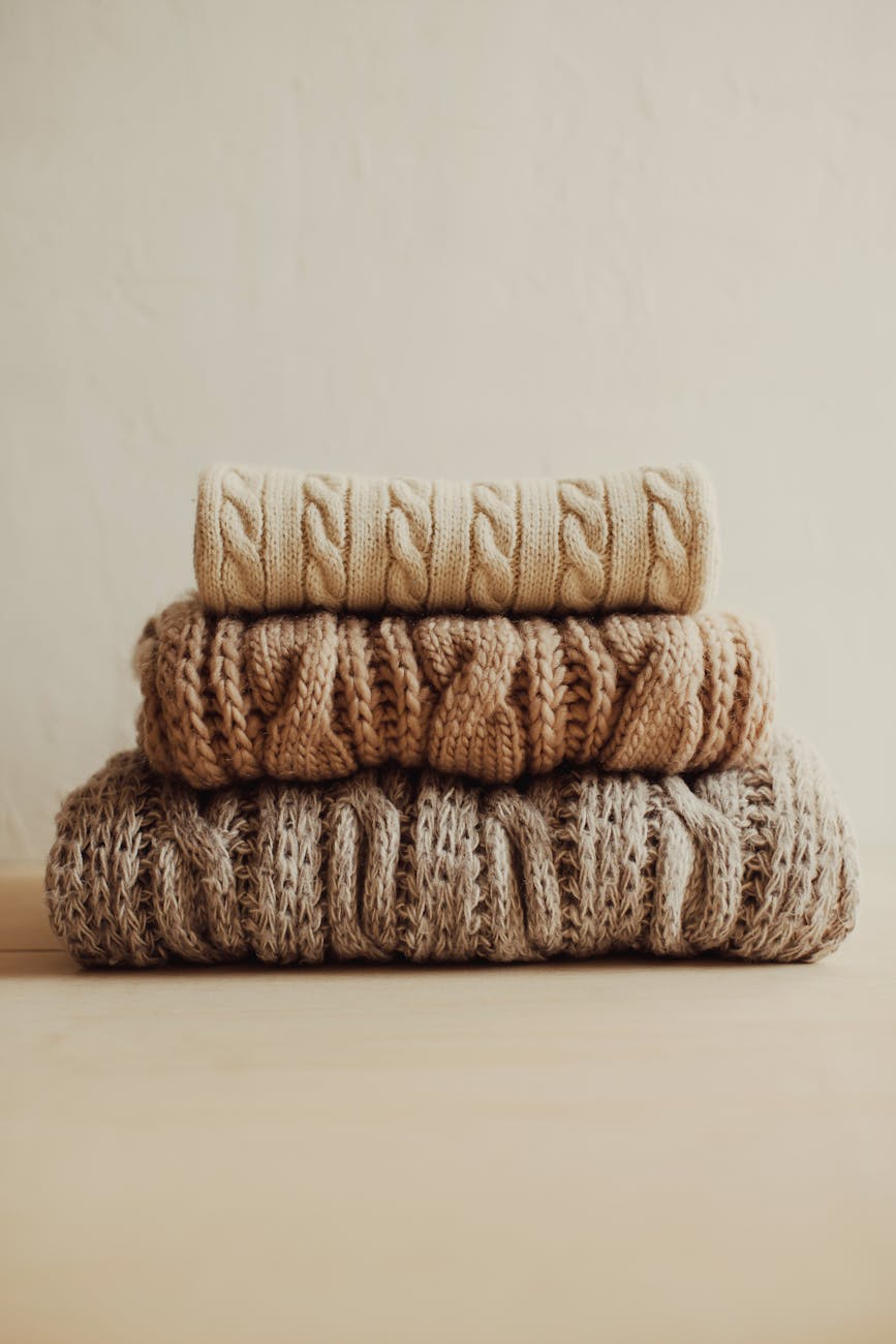 stack of knitted sweaters on white surface